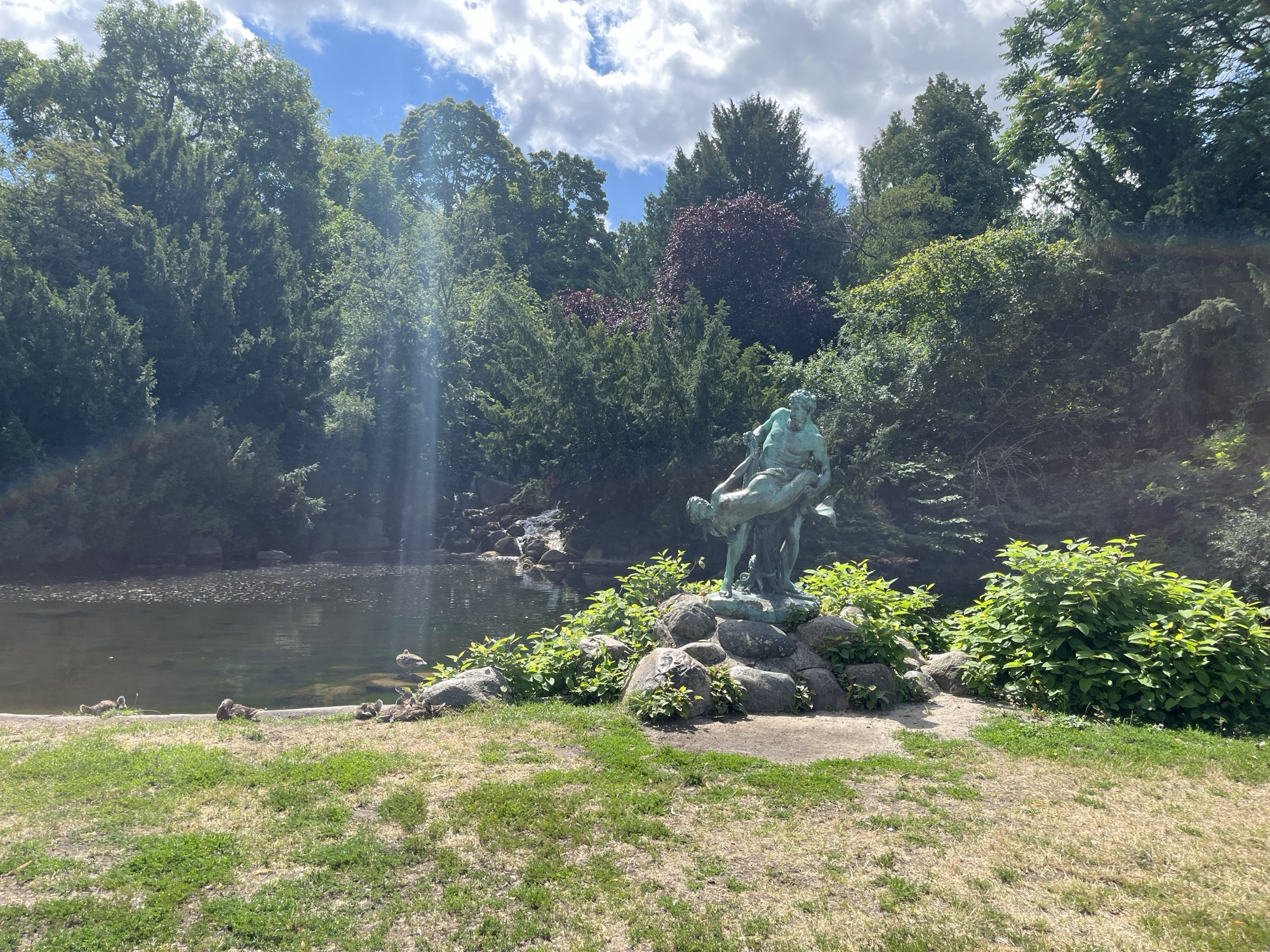 The bronze fountain statue and pond below the waterfall in Viktoriapark, ducks resting on the bank