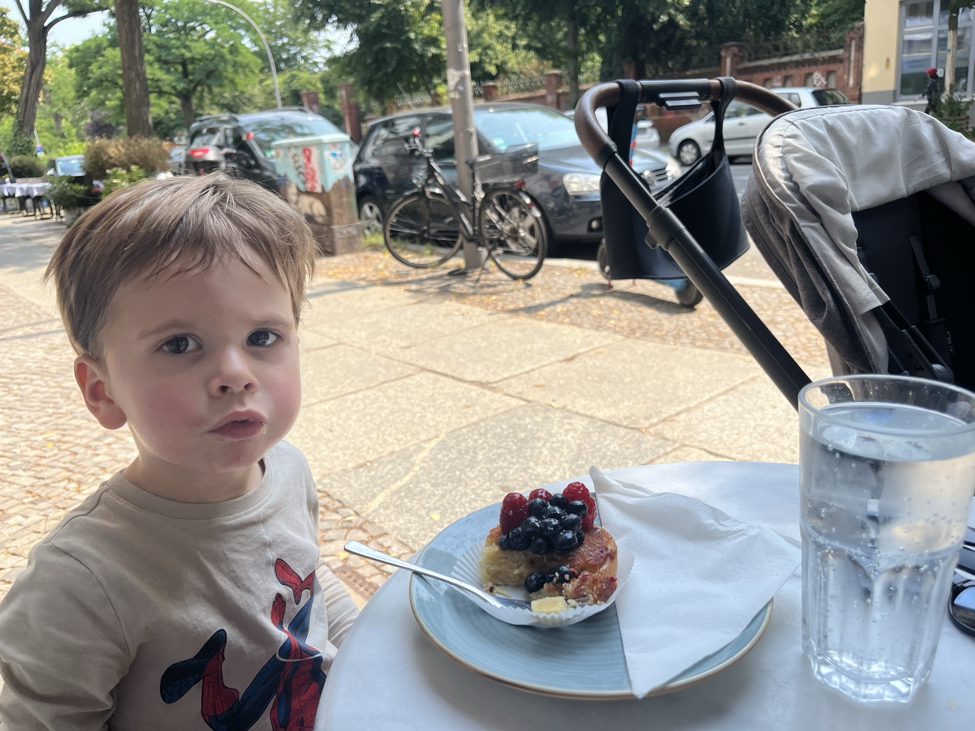 George at a sidewalk table with a berry-topped tart and a glass of sparkling water