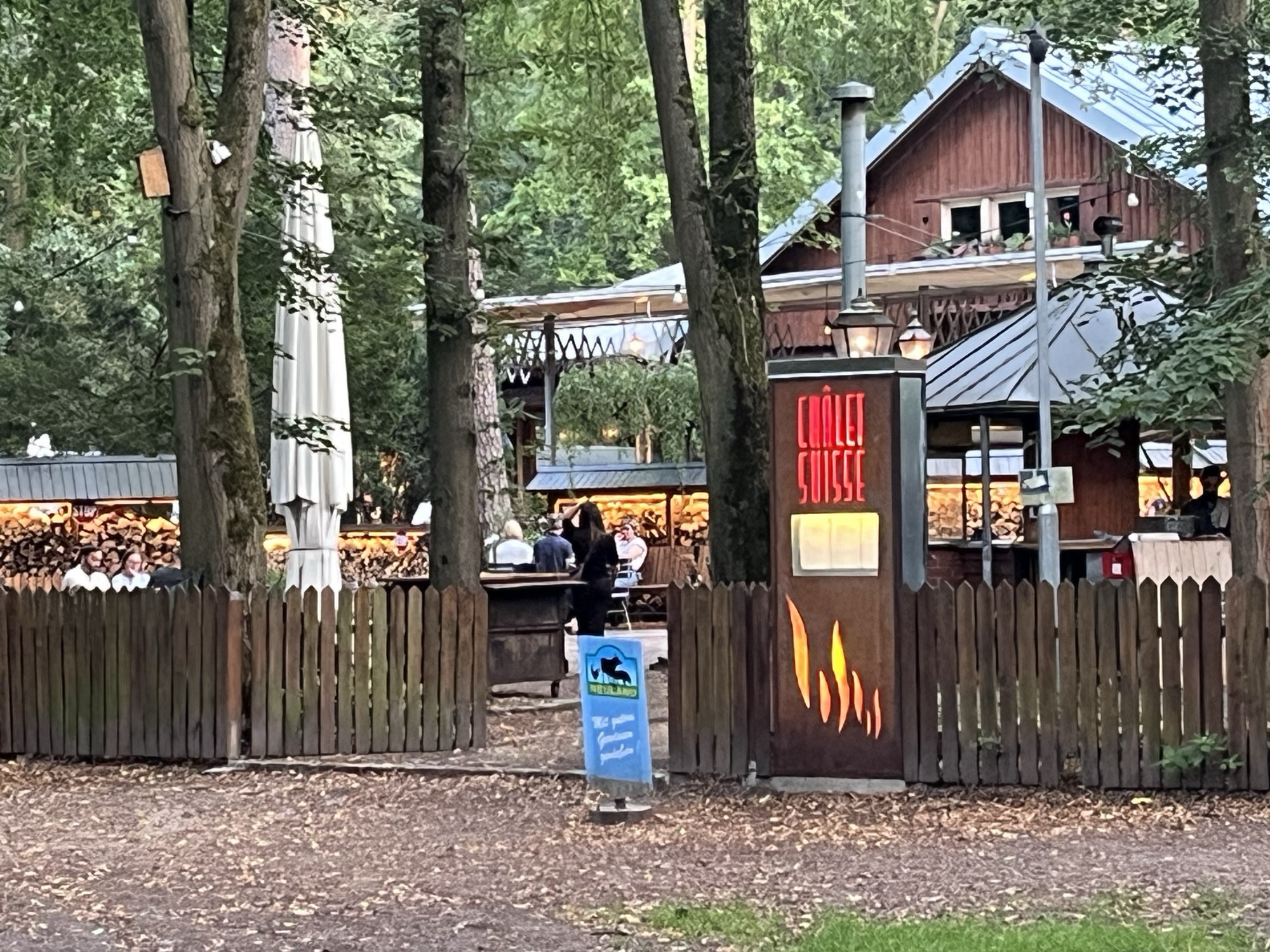 The Châlet Suisse sign glowing at the biergarten entrance, the wooden chalet among the Grunewald trees